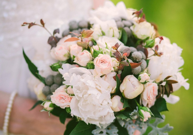 A bouquet of white and soft pink flowers held by a bride.