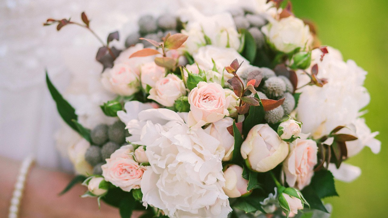 A bouquet of white and soft pink flowers held by a bride.