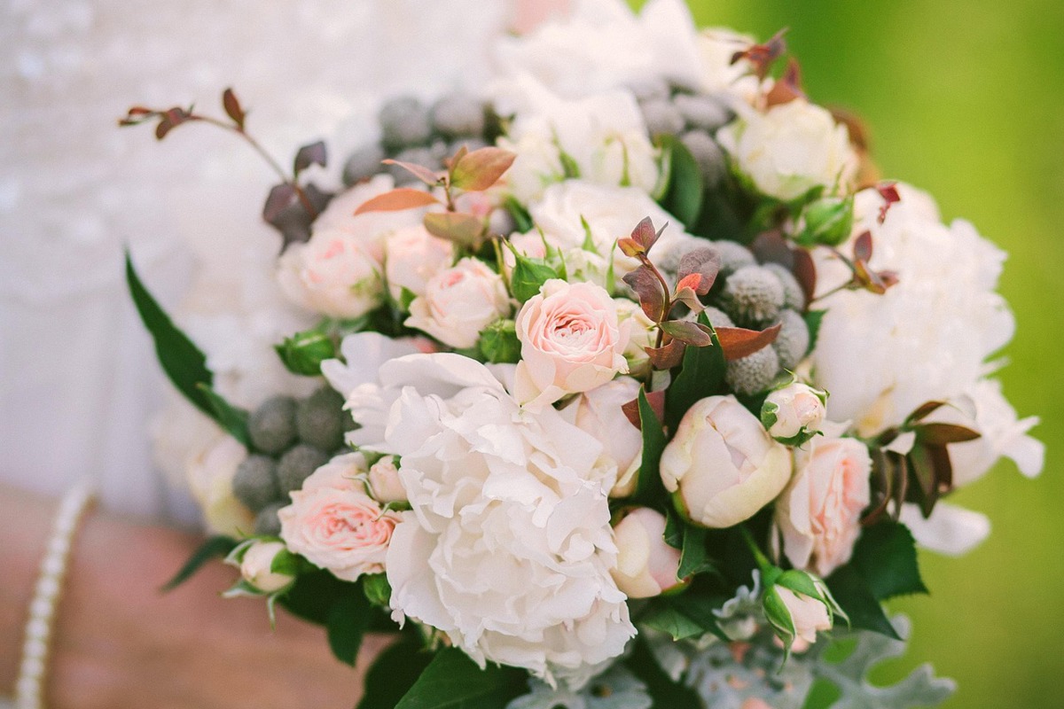 A bouquet of white and soft pink flowers held by a bride.