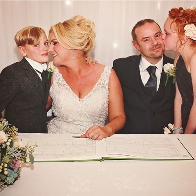Bride & Groom signing the register with their children by their side.