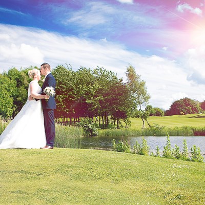 Bride and groom by the lake on the golf course.