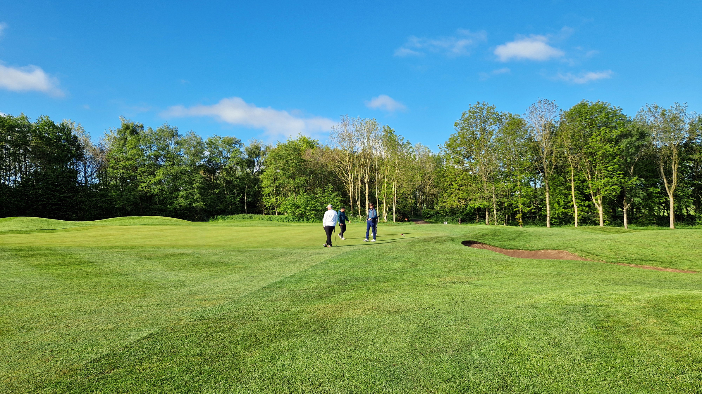 A view of 16th green at The Manor golf course, there are three male golfers.