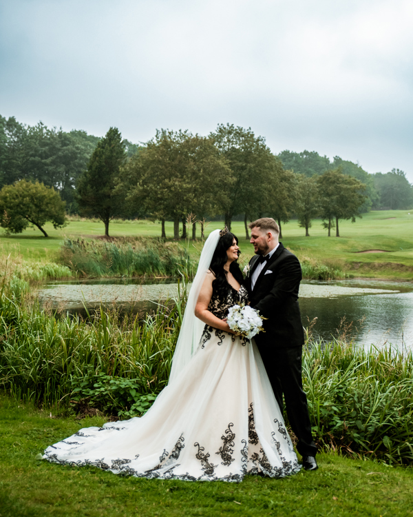 A bride and groom embrace beside The Lake at The Manor Leeds.