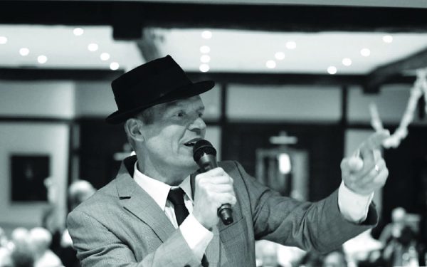 A black and white photo of Frank Sinatra tribute Phil Fryer singing into a microphone.