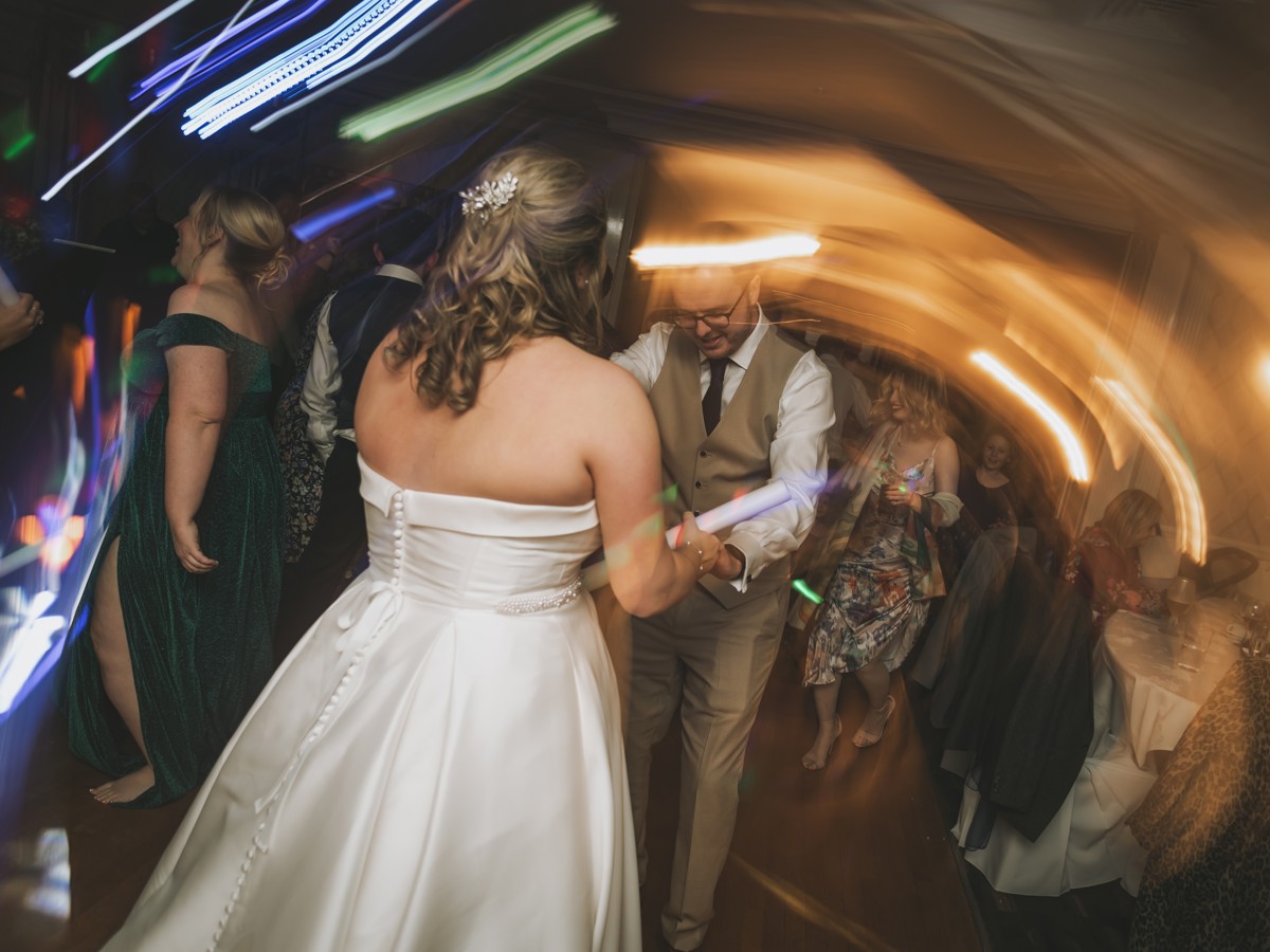An action shot of a bride and groom dancing with their guests on the dancefloor at The Manor Leeds.
