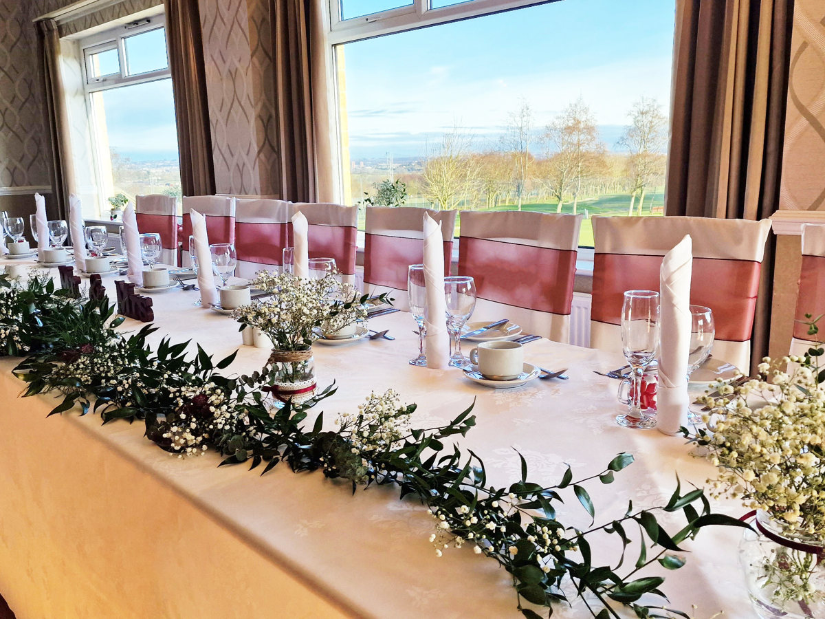 A long top-table set for a wedding breakfast in The View room of The Manor Leeds.