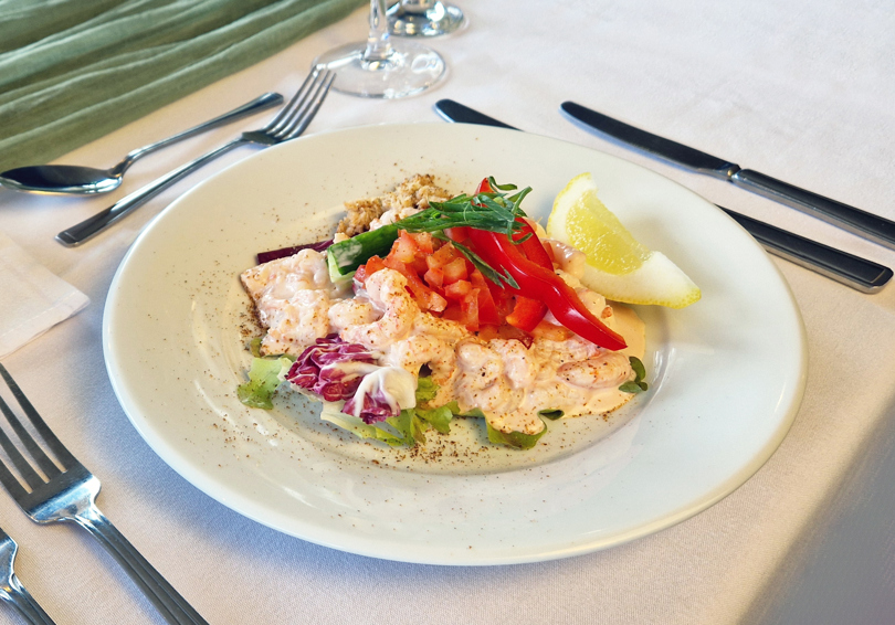 Prawn cocktail on a plate, placed on a formal dining table.