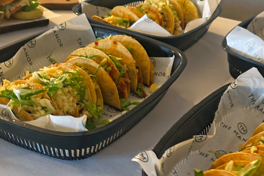 Tacos presented on baskets lined with greaseproof paper printed with The Manor logo on a buffet table at The Manor Leeds.