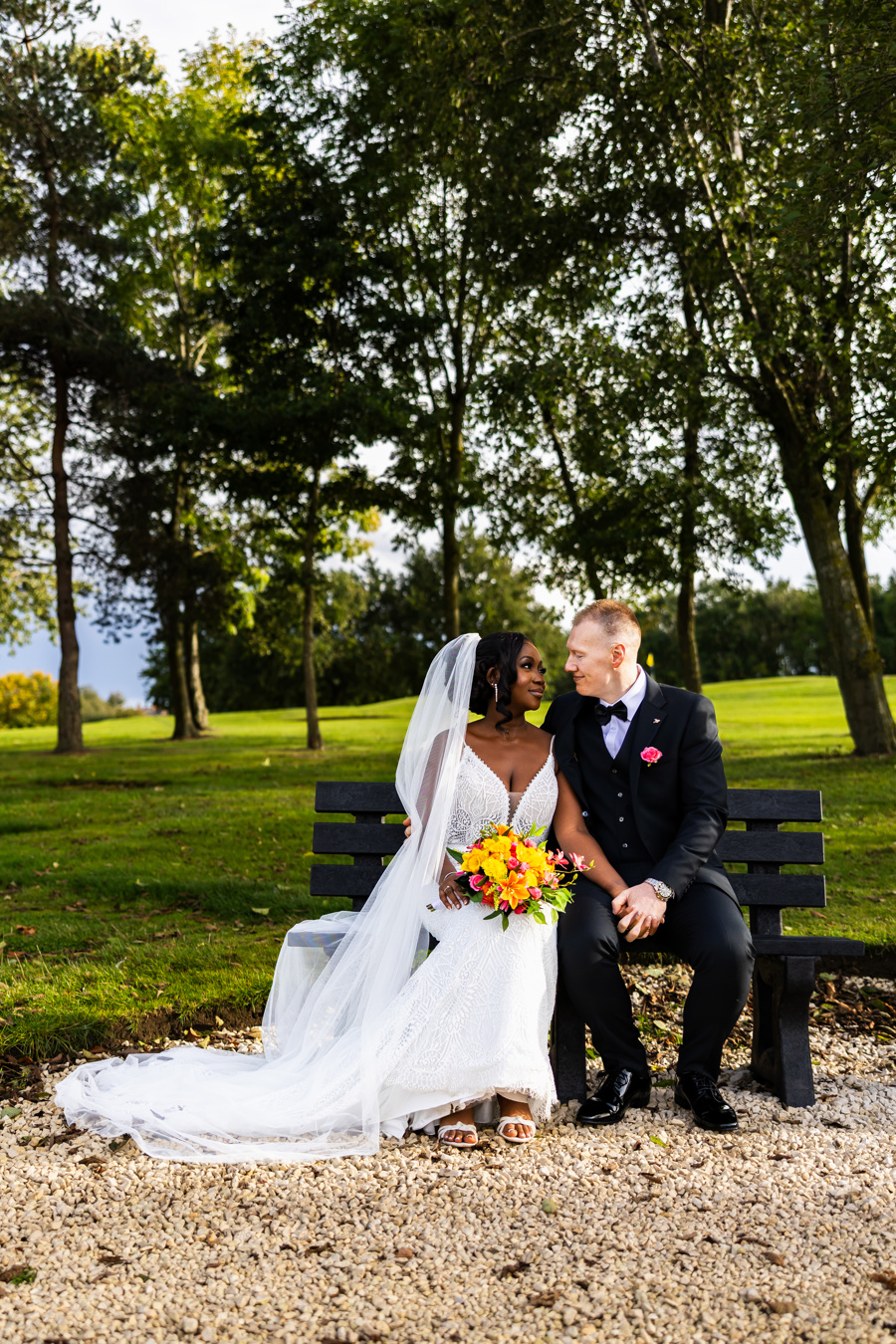 A bride and groom gaze at each other while sitting on a bench at The Manor Leeds.