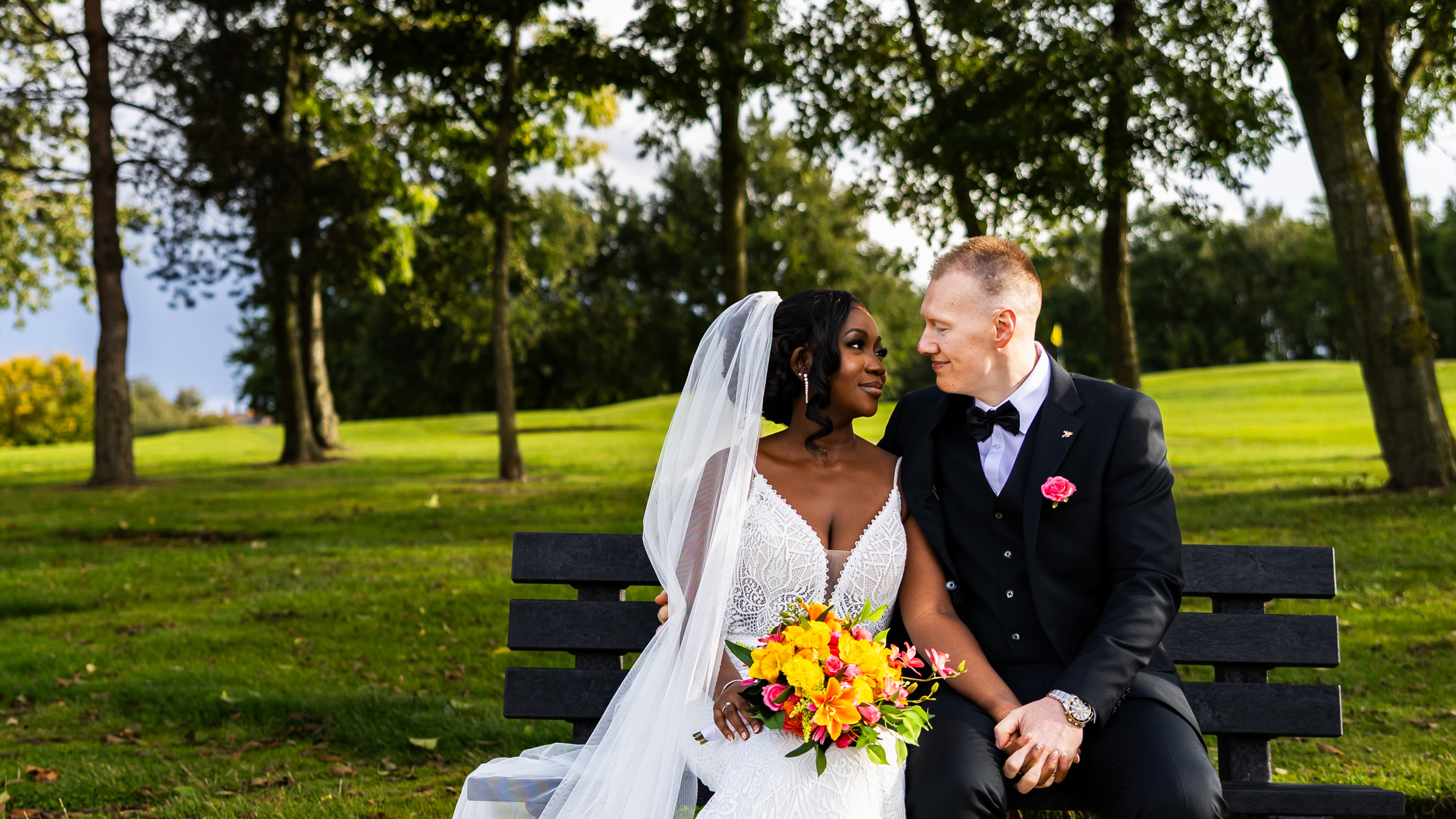 A bride and groom gaze at each other while sitting on a bench at The Manor Leeds.
