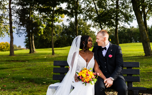 A bride and groom gaze at each other while sitting on a bench at The Manor Leeds.