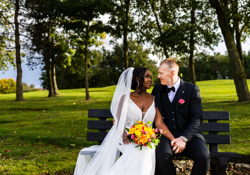 A bride and groom gaze at each other while sitting on a bench at The Manor Leeds.