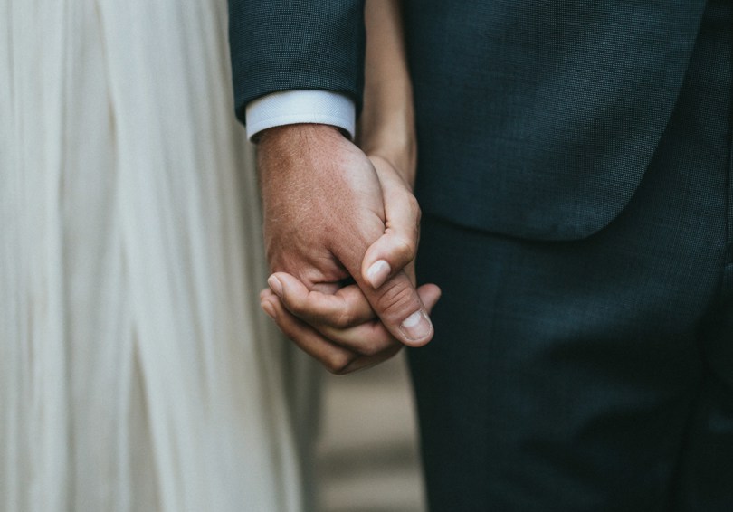 A close shot of bride and groom holding hands.
