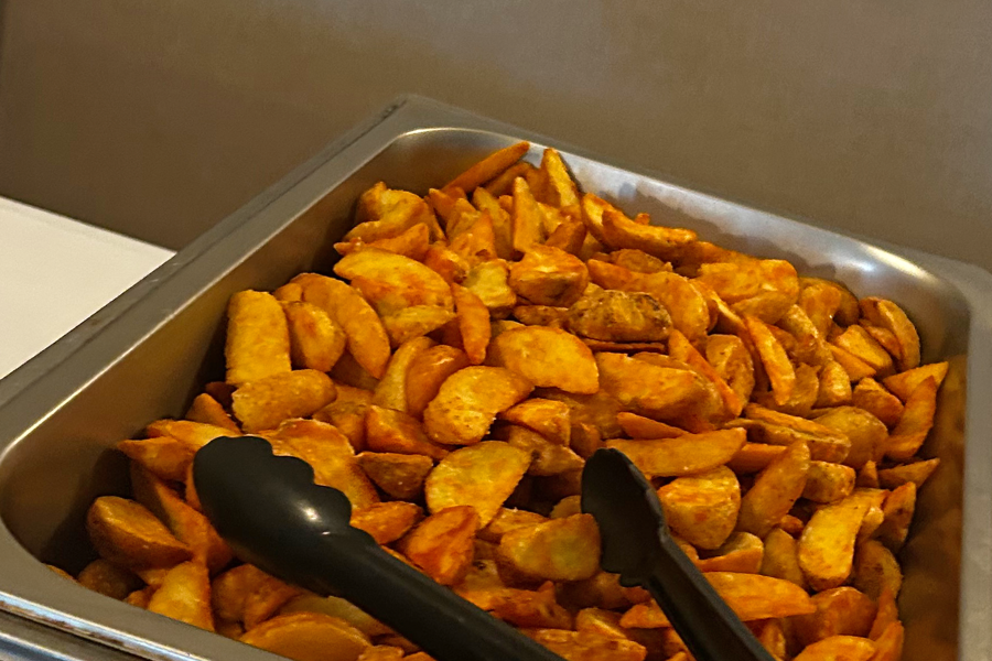 Potato wedges in a chafing dish on a buffet table at The Manor Leeds.