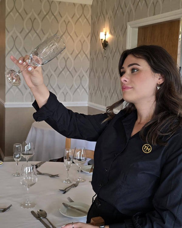 The Manor Assistant Events Manager Starr inspecting a champagne flute.