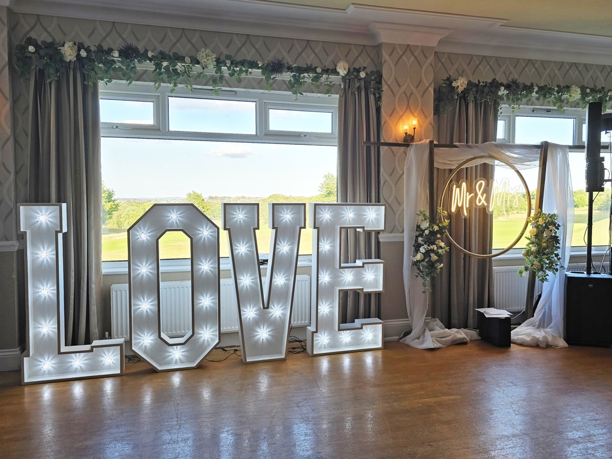 Large, white light-up letters spelling the word "LOVE" and a neon sign saying "Mr & Mrs" on the dancefloor at The Manor Leeds.