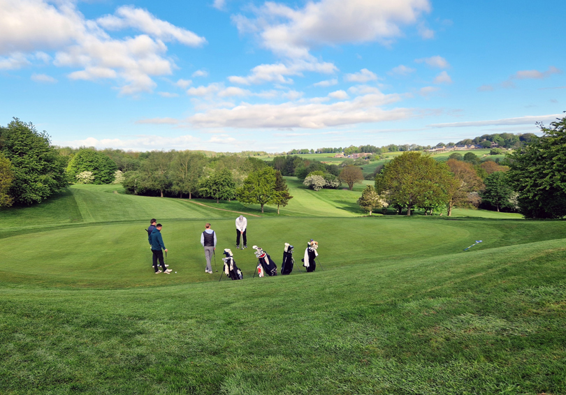 A view of 3rd green at The Manor golf course, there are four male golfers, one is putting.