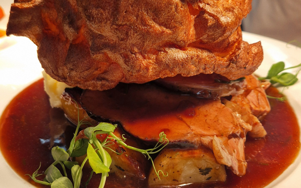 Roast dinner on a plate, Yorkshire Pudding, beef, roast potatoes and gravy.