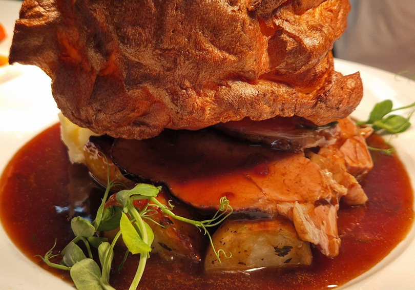 Roast dinner on a plate, Yorkshire Pudding, beef, roast potatoes and gravy.