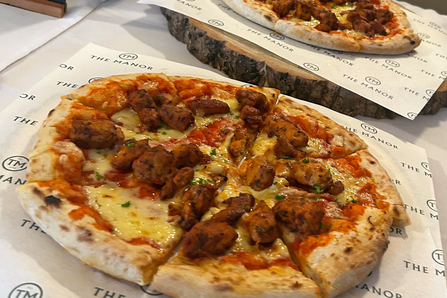 BBQ pizza presented on greaseproof paper printed with The Manor logo on a buffet table at The Manor Leeds.