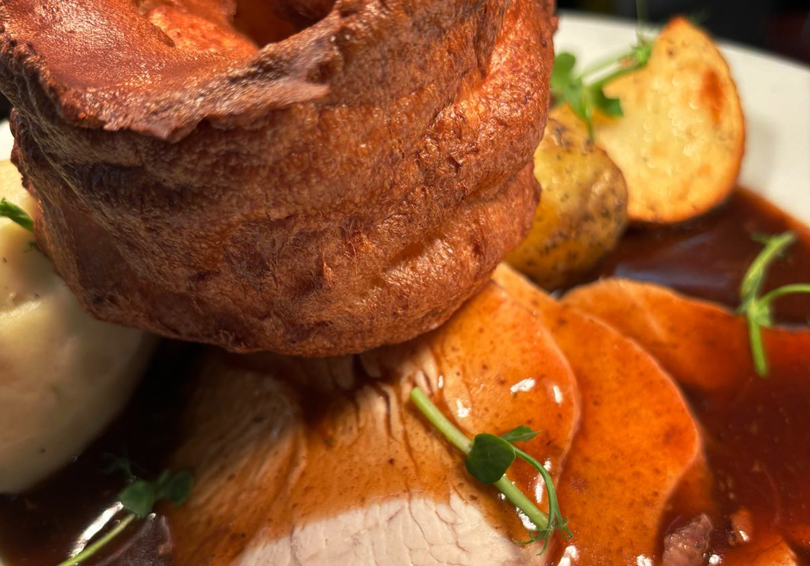 Roast dinner on a plate, Yorkshire Pudding, pork and gravy.