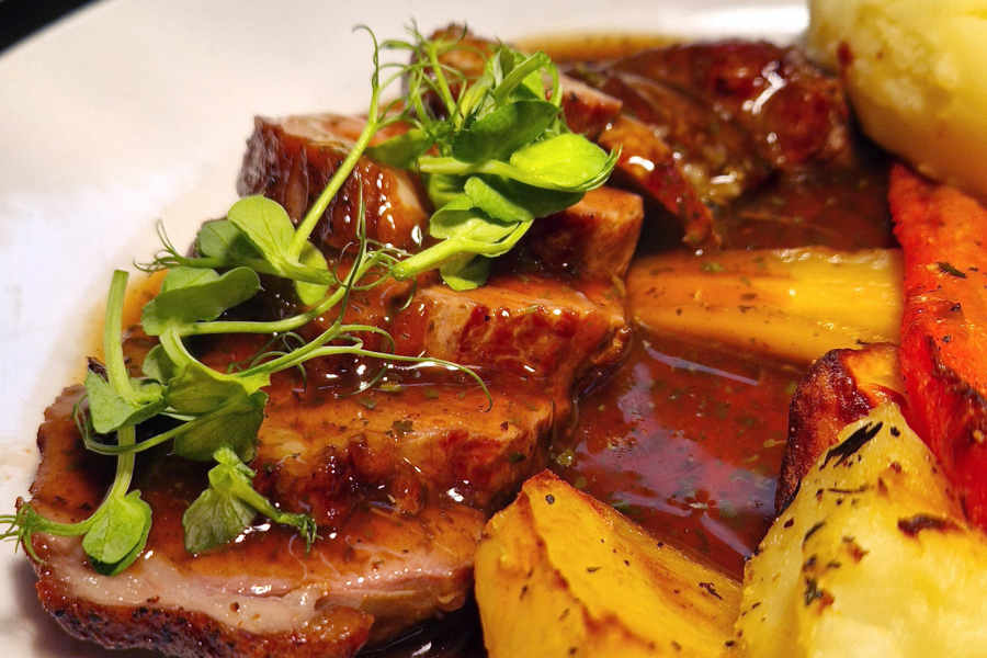 Roast lamb on a plate, with roast potatoes and minted gravy.