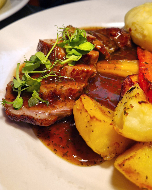 Roast lamb on a plate, with roast potatoes and minted gravy.