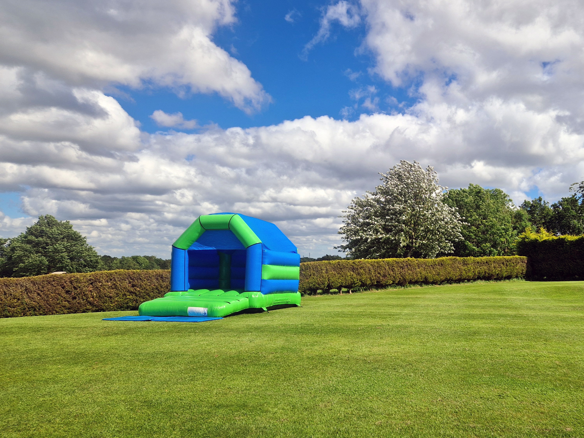 A blue and green bouncy castle on The Lawn at The Manor Leeds.