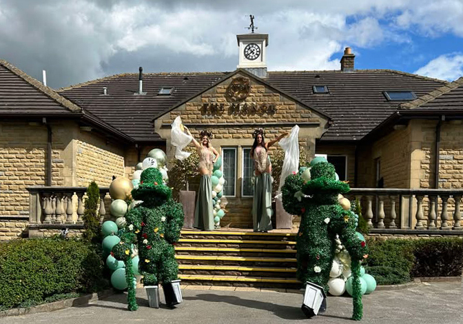 Stilt walkers pose by the main entrance of The Manor Leeds.
