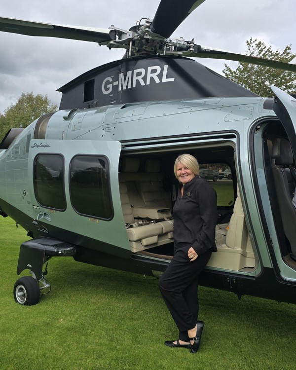 The Manor Events Manager Becky standing infront of a helicopter.