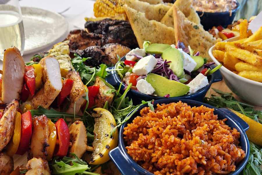 The Peri-Peri sharing board at The Manor Leeds; Peri-Peri Chicken Thighs, Grilled Chicken & Pepper Skewers, Grilled Halloumi & Pepper Skewers, Garlic Bread, Spicy Rice, Corn on the Cob, Skin-on Wedges, Peri-Peri Coleslaw and Rainbow Leaf Salad.
