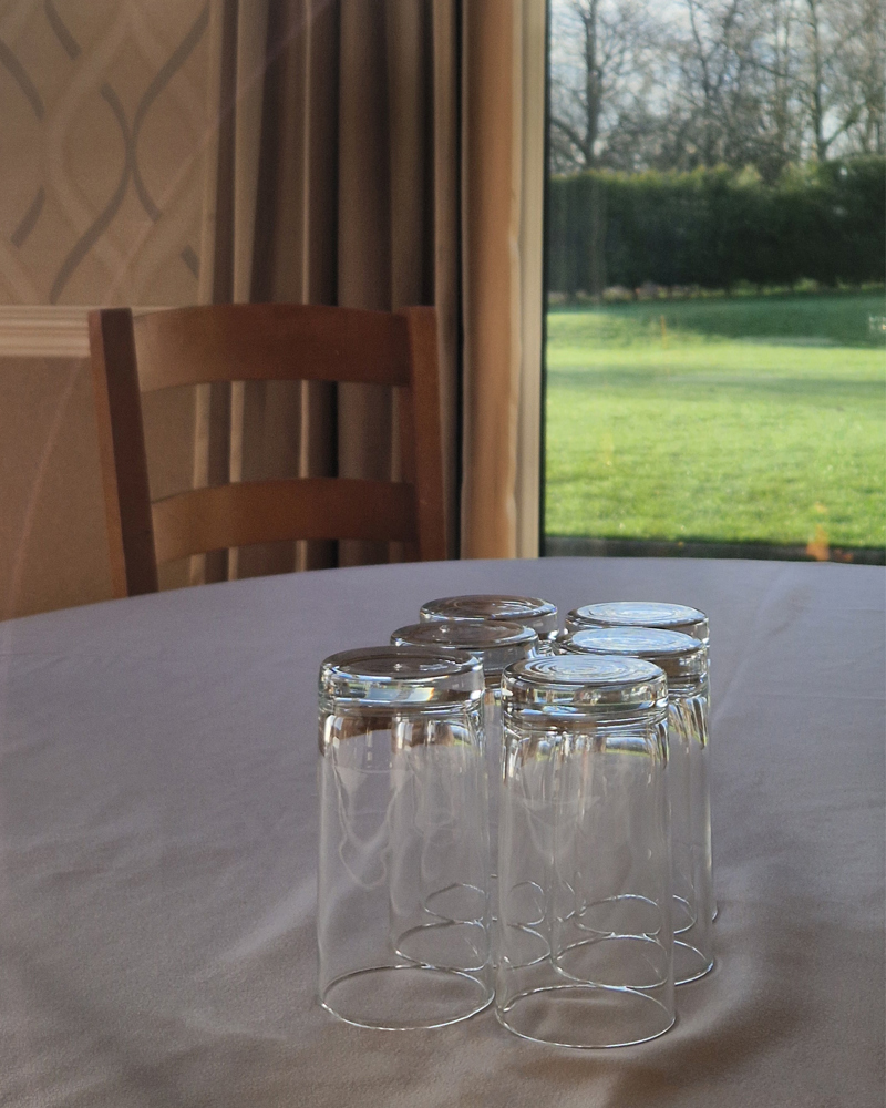 Six water glasses placed upturned on a table.